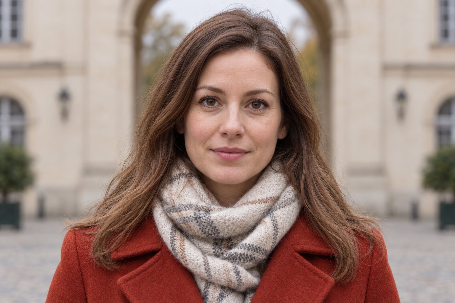 Tight portrait of a woman in a red coat; eyes and face fill most of the image