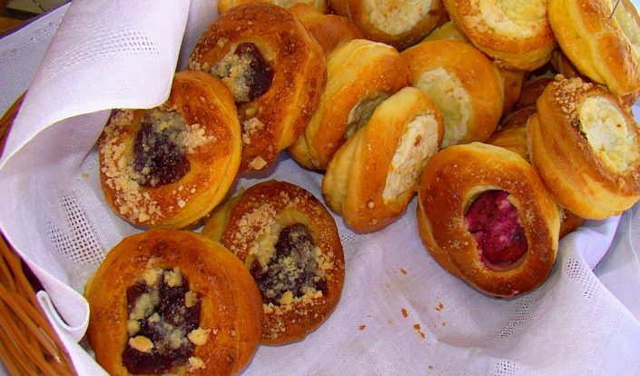Okrągłe drożdżówki z białym serem oraz z ciemnym nadzieniem i kruszonką w koszyku pod lnianą serwetą, z Sanoka