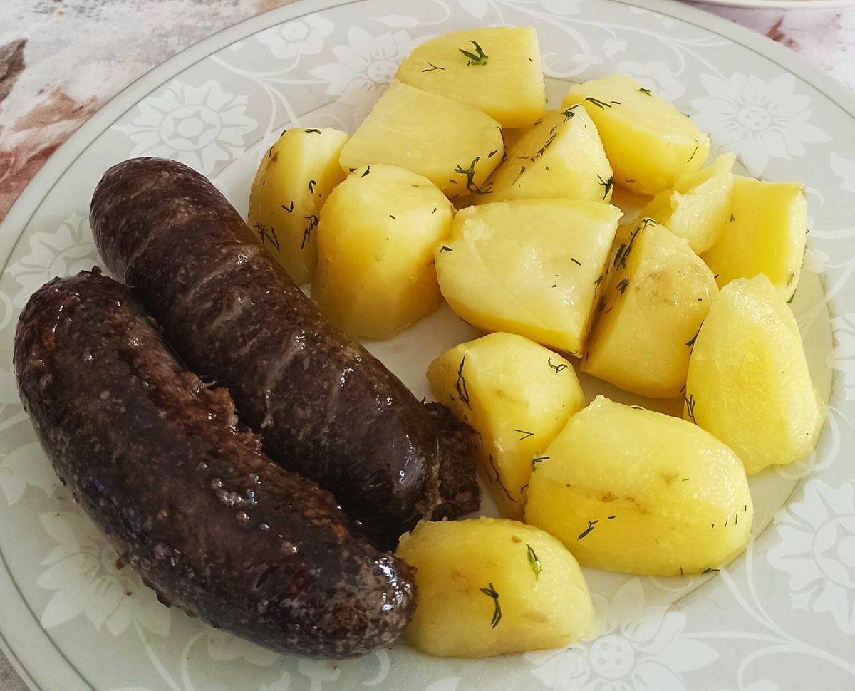 Dwie kaszanki w całości, w osłonce, z gotowanymi ziemniakami z koperkiem