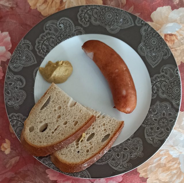 Kiełbasa śląska z musztardą i kromkami chleba na talerzu