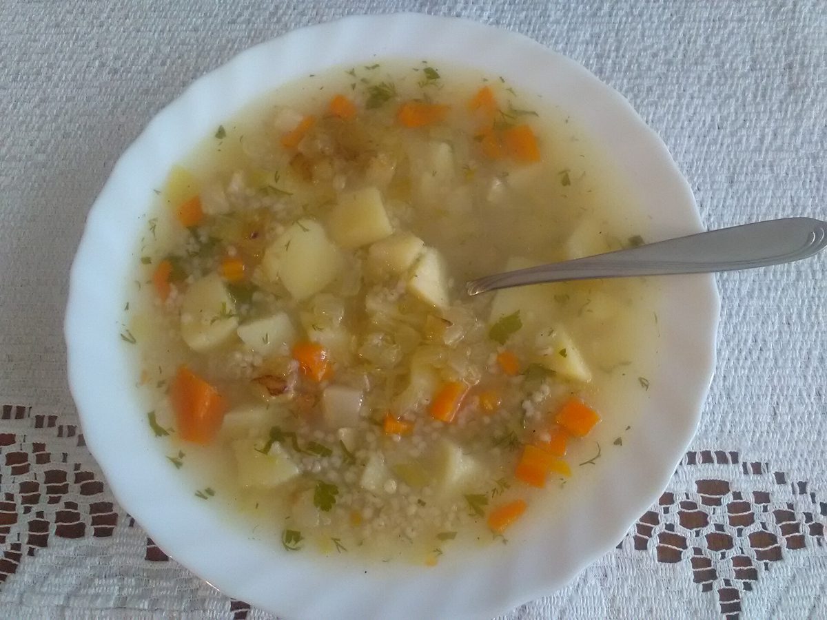 Gęsty krupnik z ziemniakami i łyżką w misce