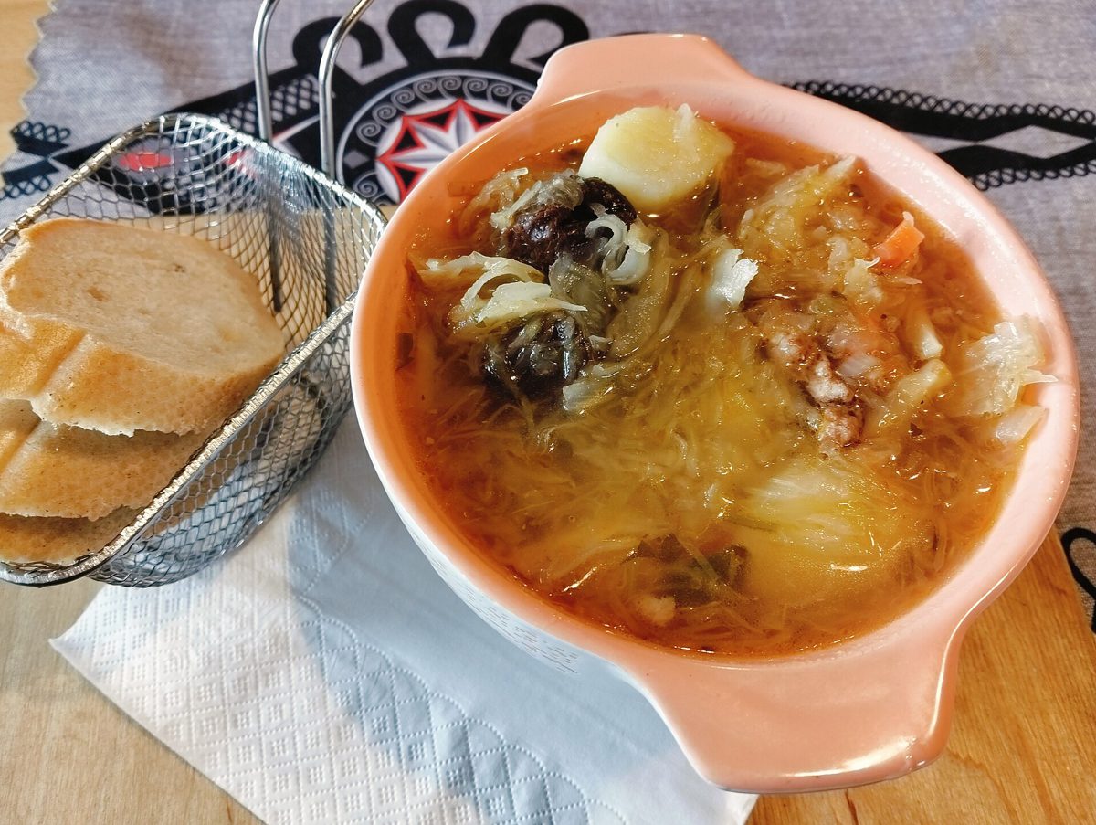 Kwaśnica z kapustą, ziemniakiem, suszonymi grzybami i mięsem w gospodzie w Łącku, obok pieczywo w koszyku