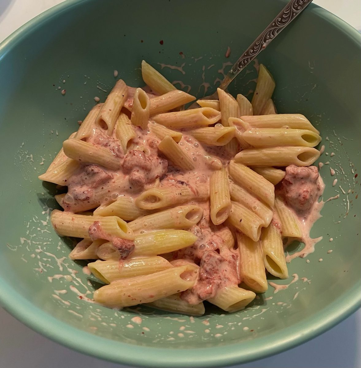 Makaron penne wymieszany z rozgniecionymi truskawkami i śmietaną w zielonej misce