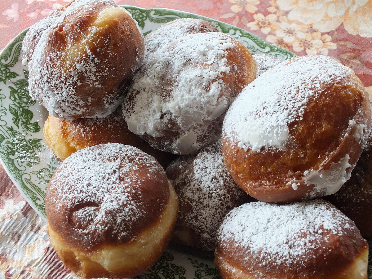 Domowe pączki posypane cukrem pudrem na talerzu w zielony wzór