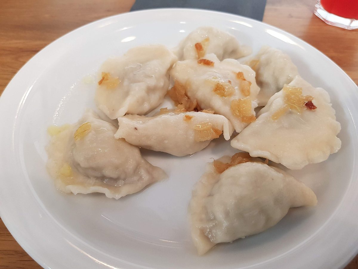 Pierogi ruskie z cebulką na białym talerzu