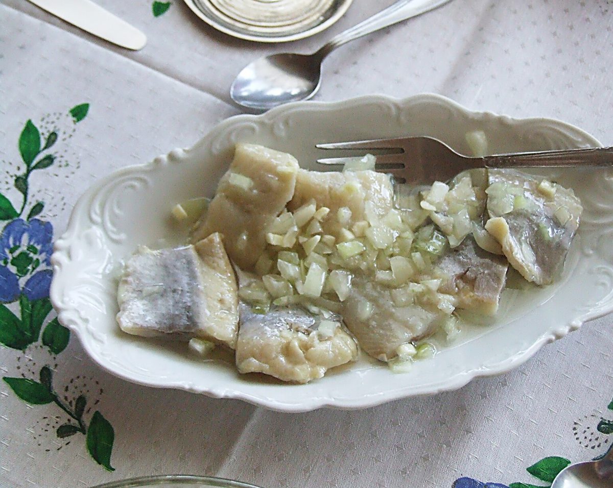 Kawałki śledzia w oleju z drobno pokrojoną cebulą na domowym stole