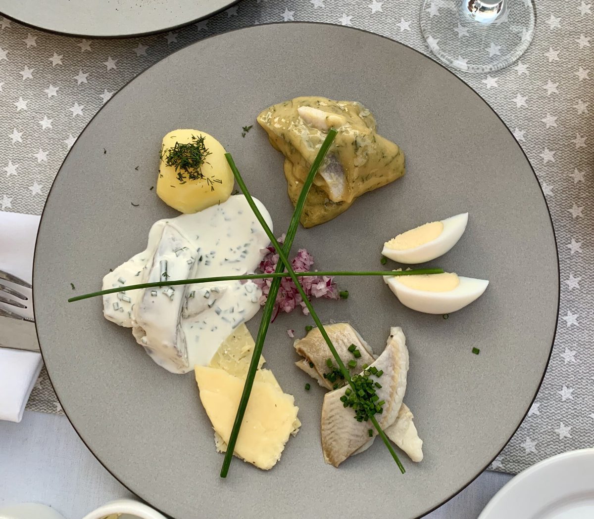 Talerz śledzi w restauracji w Krakowie: śledź w sosie śmietanowym ze szczypiorkiem, śledź w sosie musztardowym, ziemniak z koperkiem i jajko